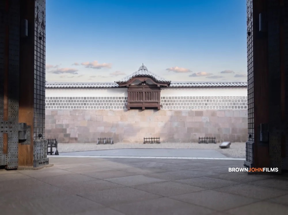 View through a heavy wooden castle gate to a white castle wall under blue sky